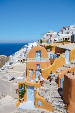 Couple on vacation in Santorini Greece, and men and women at the Greek village of Oia with a view over the ocean during summer vacation