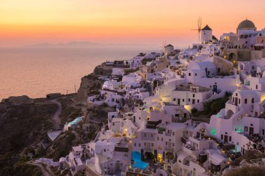 sunset with white churches an blue domes by the ocean of Oia Santorini Greece, a traditional Greek village in Santorini. 