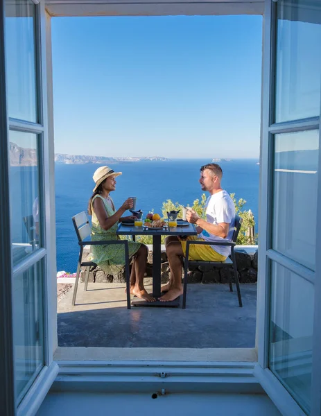 Couple on vacation in Santorini Greece, men and women having breakfast in a traditional dome house during vacation in Santorini Greece