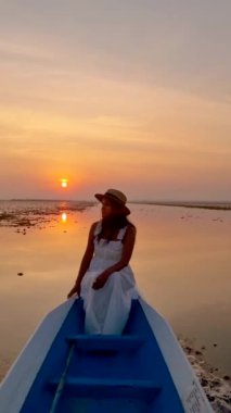 Sunrise at The sea of red lotus, Lake Nong Harn, Udon Thani, Thailand. An Asian woman in a wooden boat during sunrise at the red lotus lake in Thailand Isaan region