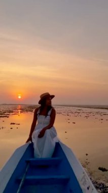 Sunrise at The sea of red lotus, Lake Nong Harn, Udon Thani, Thailand. A Asian women in a wooden boat during sunrise at the red lotus lake in Thailand 