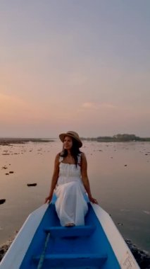 Sunrise at The sea of red lotus, Lake Nong Harn, Udon Thani, Thailand. An Asian woman in a wooden boat during sunrise at the red lotus lake in Thailand 