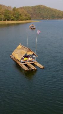 Men and women at a bamboo raft at Huai Krathing lake in North Eastern Thailand Isaan region, famous for its floating bamboo rafts where you can have lunch or dinner in the middle of the lake. 