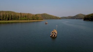 Men and women at a bamboo raft at Huai Krathing lake in North Eastern Thailand Isaan region, famous for its floating bamboo rafts where you can have lunch or dinner in the middle of the lake. 