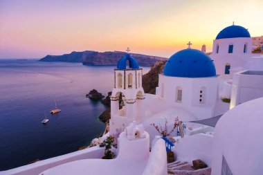 White churches an blue domes by the ocean of Oia Santorini Greece, a traditional Greek village in Santorini during summer