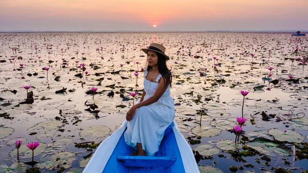 Asian women in a boat at the Beautiful Red Lotus Sea full of pink flowers in Udon Thani in northern Thailand. Flora of Southeast Asia.