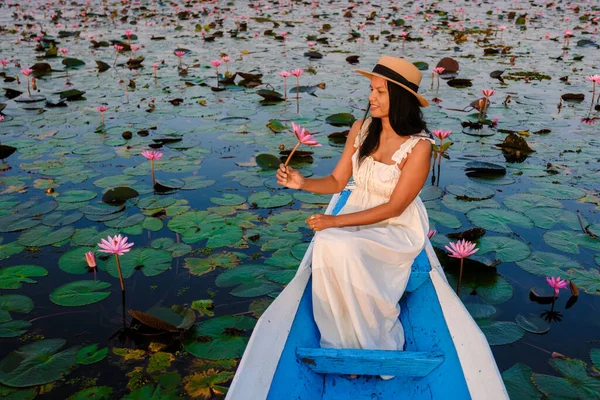 Thai women in a boat at the Beautiful Red Lotus Sea Kumphawapi is full of pink flowers in Udon Thani in northern Thailand. Flora of Southeast Asia.