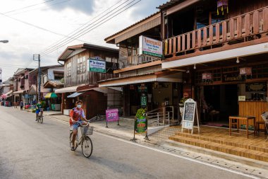 Chiang Khan Köyü Kuzey Doğu Tayland Şubat 2023, Mekong nehri kıyısında bisiklet süren insanlar. Ahşap evi olan geleneksel bir köy Chiang Khan