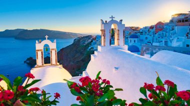Santorini 'deki geleneksel bir Yunan köyü olan Oia Santorini' nin okyanus kıyısında gün batımı beyazlatılmış kiliseler ve mavi kubbeler ile
