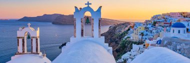 White churches an blue domes by the ocean of Oia Santorini Greece, a traditional Greek village in Santorini during summer