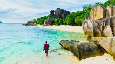 Young men at a white tropical beach Anse Source dArgent beach La Digue Seychelles Islands.