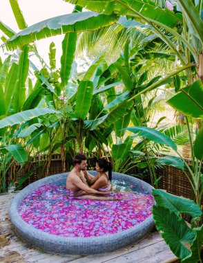 Tatil sırasında Tayland yağmur ormanlarındaki bir küvette banyo yapan bir çift, erkekler ve kadınlar dışarıda gül yapraklarıyla jakuzide dinleniyorlar. Sevgililer Günü Kutlaması