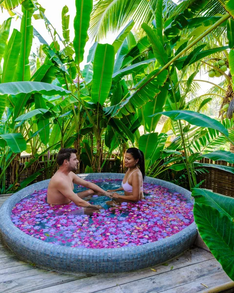 Tatil sırasında Tayland yağmur ormanlarındaki bir küvette banyo yapan bir çift, erkekler ve kadınlar dışarıda gül yapraklarıyla jakuzide dinleniyorlar. Sevgililer Günü Kutlaması