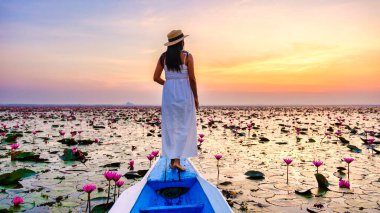 Asian women in a boat at the Beautiful Red Lotus Sea Kumphawapi is full of pink flowers in Udon Thani in Northern Thailand Isaan. Flora of Southeast Asia.