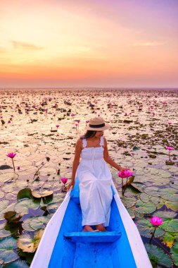 Asian women in a boat at the Beautiful Red Lotus Sea Kumphawapi is full of pink flowers in Udon Thani in northern Thailand. Flora of Southeast Asia.