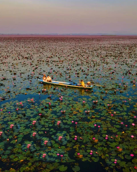 赤い蓮の海での日の出 ハーン湖 うどんタイ タイの赤い蓮の湖で日の出の間に木製のボートの男性と女性のカップル — ストック写真