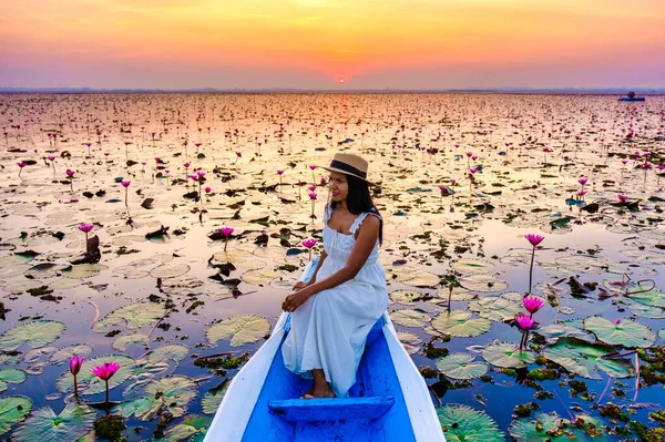 Thai women in a boat at the Beautiful Red Lotus Sea Kumphawapi is full of pink flowers in Udon Thani in northern Thailand. Flora of Southeast Asia.