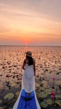 Asian women in a boat at the Beautiful Red Lotus Sea Kumphawapi is full of pink flowers in Udon Thani in Northern Thailand Isaan. Flora of Southeast Asia. 