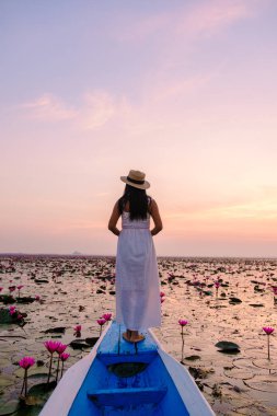 Kızıl Lotus Denizi, Nong Harn Gölü, Udon Thani, Tayland, Asyalı kadın elbise ve şapkalı kırmızı Lotus Gölü 'ndeki ahşap bir teknede.. 