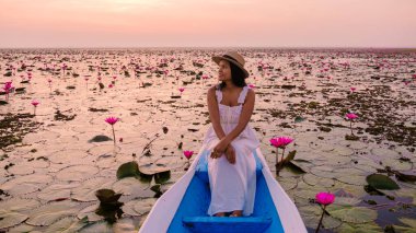 Kızıl Lotus Denizi, Nong Harn Gölü, Udon Thani, Tayland, Asyalı kadın elbise ve şapkalı kırmızı Lotus Gölü 'ndeki ahşap bir teknede.. 