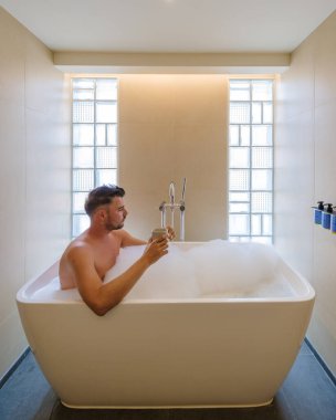 Lüks bir otel odasında beyaz küvette genç erkekler, klasik banyo.. 