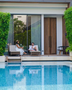 Asya 'da lüks 5 yıldızlı otel havuzu. Lüks bir otelde tatil yapan birkaç erkek ve kadın, havuz başında beyaz erkekler ve Taylandlı kadınlar.