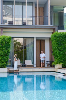 Asya 'da lüks 5 yıldızlı otel havuzu. Lüks bir otelde tatil yapan birkaç erkek ve kadın, havuz başında beyaz erkekler ve Taylandlı kadınlar.