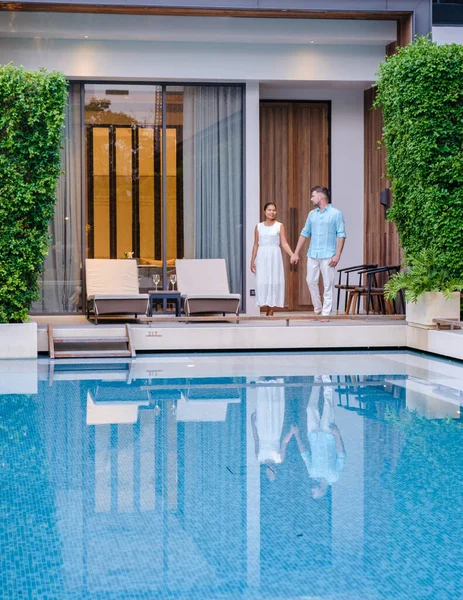 Luxury 5 star hotel pool in Asia. A couple of men and women on vacation at a luxury hotel resort, caucasian men and Thai women by the pool
