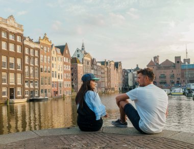 Amsterdam Damrak günbatımında, mutlu bir çift yaz akşamı kanallarda, Amsterdam Dansçı Evi 'nin yanındaki Waterfront' ta bir Hollandalı çift