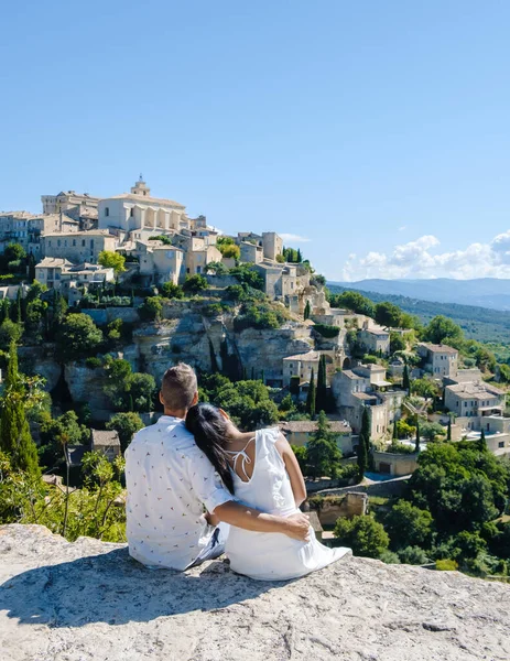 A couple of men and women on vacation in Southern France looking out over the old historical village of Gordes Luberon Provence during summer
