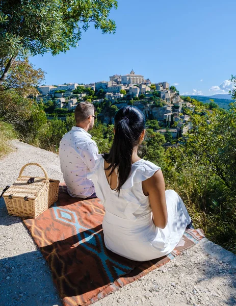 A couple of men and women on vacation in Southern France looking out over the old historical village of Gordes Luberon Provence
