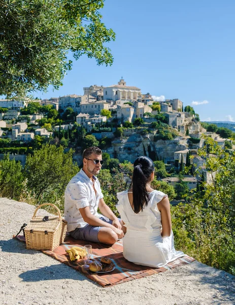 A couple of men and women on vacation in Southern France looking out over the old historical village of Gordes Luberon Provence