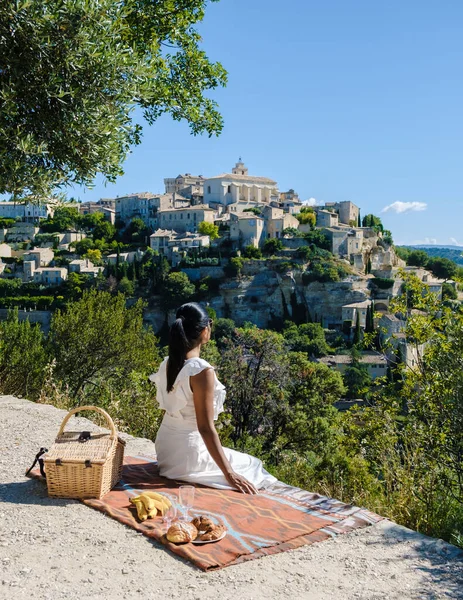 A couple of men and women on vacation in Southern France looking out over the old historical village of Gordes Luberon Provence during summer