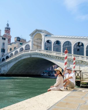 İtalya Venedik 'te, İtalya' da Rialto Köprüsü 'nün rıhtımında şehir gezisinde olan iki erkek ve kadın. Venedik 'in mimarisi ve simgesi. İtalya' nın Venedik şehri yaz boyunca.