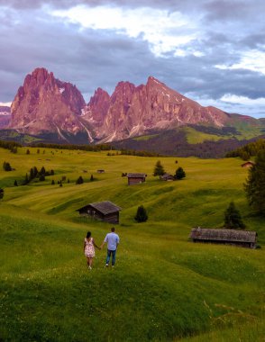 Seiser Alm Sassolungo Langkofel dağ grubuyla birlikte gün batımında Alpe di Siusi Dağı 'nda. İtalya 'nın Dolomitler Dağları' nda gün batımını izleyen bir çift erkek ve kadın.
