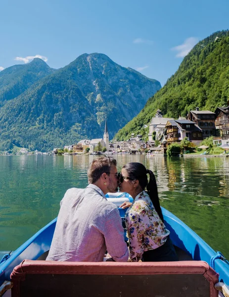 A couple of men and women in an electric boat on the lake on vacation in Hallstatt Salzkammergut, Austria, Hallstatt village on Hallstatt lake in the Austrian Alps Austria Europe at sunset.
