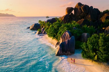 Anse Source dArgent, La Digue Seychelles, Seyşeller 'de lüks bir tatil sırasında tropikal bir plajda yaşayan genç bir çift. Tropik sahil Anse Kaynak dArgent, La Digue Seyşeller