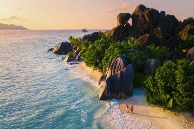 Anse Source dArgent, La Digue Seychelles, a young couple of men and women on a tropical beach during a luxury vacation in Seychelles. Tropical beach Anse Source dArgent, La Digue Seychelles clipart
