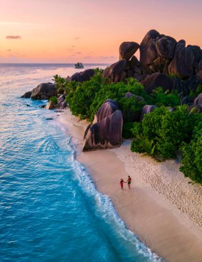 Anse Source dArgent, La Digue Seychelles, Anse Source DArgent, La Digue Seychelles 'de lüks bir tatil sırasında tropikal bir plajda yaşayan birkaç beyaz erkek ve Asyalı kadın.