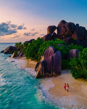 Anse Source dArgent, La Digue Seychelles, Anse Source DArgent, La Digue Seychelles 'de lüks bir tatil sırasında tropikal bir plajda yaşayan birkaç beyaz erkek ve Asyalı kadın.