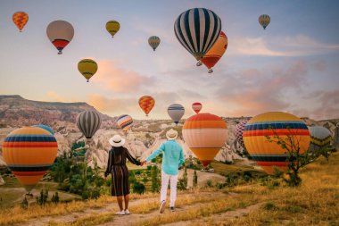 Gündoğumunda Kapadokya Türkiye, Goreme Capadocia Türkiye tepelerinde tatil yapan iki orta yaşlı erkek ve kadın, Kapadokya Türkiye 'de sıcak hava balonlarıyla güneşlenen erkekler ve kadınlar