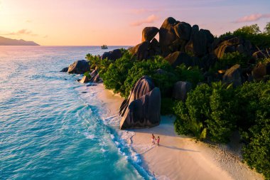 Anse Source dArgent, La Digue Seychelles, Seyşeller 'de lüks bir tatil sırasında tropikal bir plajda yaşayan genç bir çift. Tropik sahil Anse Kaynak dArgent, La Digue Seyşeller