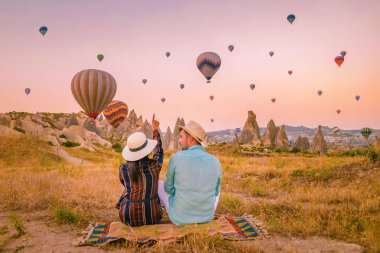 Gündoğumunda Kapadokya Türkiye, Goreme Capadocia Türkiye tepelerinde tatil yapan iki orta yaşlı erkek ve kadın, Kapadokya Türkiye 'de sıcak hava balonlarıyla güneşlenen erkekler ve kadınlar
