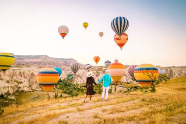 Gündoğumunda Kapadokya Türkiye, Goreme Capadocia Türkiye tepelerinde tatil yapan iki orta yaşlı erkek ve kadın, Kapadokya Türkiye 'de sıcak hava balonlarıyla güneşlenen erkekler ve kadınlar