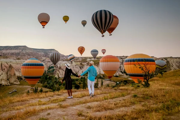 在日出期间 土耳其卡帕多西亚 一对中年男女在土耳其哥雷姆卡巴多西亚山区度假 男人和女人在土耳其卡帕多西亚拿着热气球晒太阳 — 图库照片