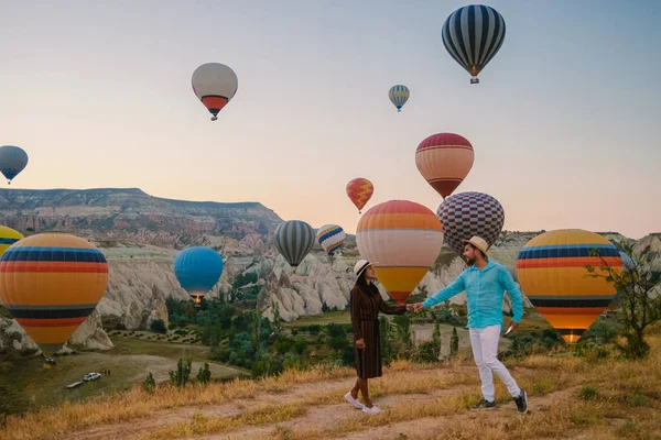 カパドキヤ カッパドキア トルコ 休暇中にカパドキヤ カッパドキア トルコの熱気球を見ている日の出の間に幸せな若いカップル — ストック写真
