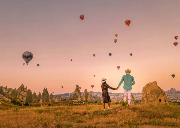 在日出期间 土耳其卡帕多西亚 一对中年男女在土耳其哥雷姆卡巴多西亚山区度假 男人和女人在土耳其卡帕多西亚拿着热气球晒太阳 — 图库照片