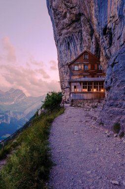 Gün batımında Den Appenzeller Alpen 'de Berggasthaus Aescher, İsviçre' de Ebenalp Dağı 'ndaki bir uçurumun altında restoran, Appenzell