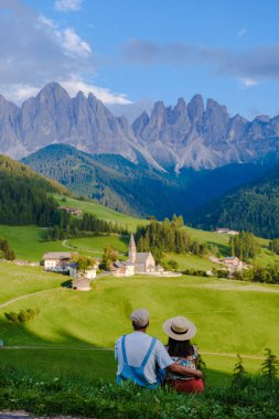 Couple viewing the landscape of Santa Maddalena Village Val di Funes, South Tyrol, Italy Dolomites, men and women visit Dolomites mountains, Val di Funes valley, Trentino Alto Adige, South Tyrol clipart