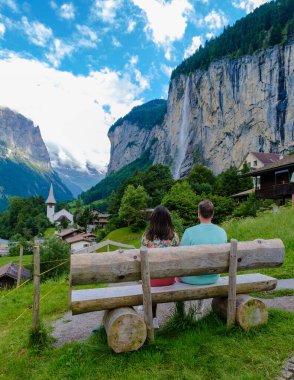 Lauterbrunnen Vadisi 'nde muhteşem bir şelale ve arka planda İsviçre Alpleri olan Berner Oberland, İsviçre ve Avrupa' yı ziyaret eden iki erkek ve kadın.. 